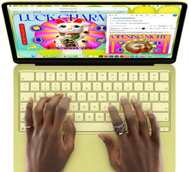 MacBook Neo amarelo-cítrico. As mãos de uma pessoa estão no teclado redigindo um e-mail com convite para uma exposição de arte. O site do evento está aberto ao lado