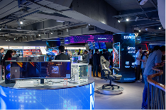 Pessoas visitam espaço com cadeiras gamer, monitores, gabinetes e mais produtos para jogos.